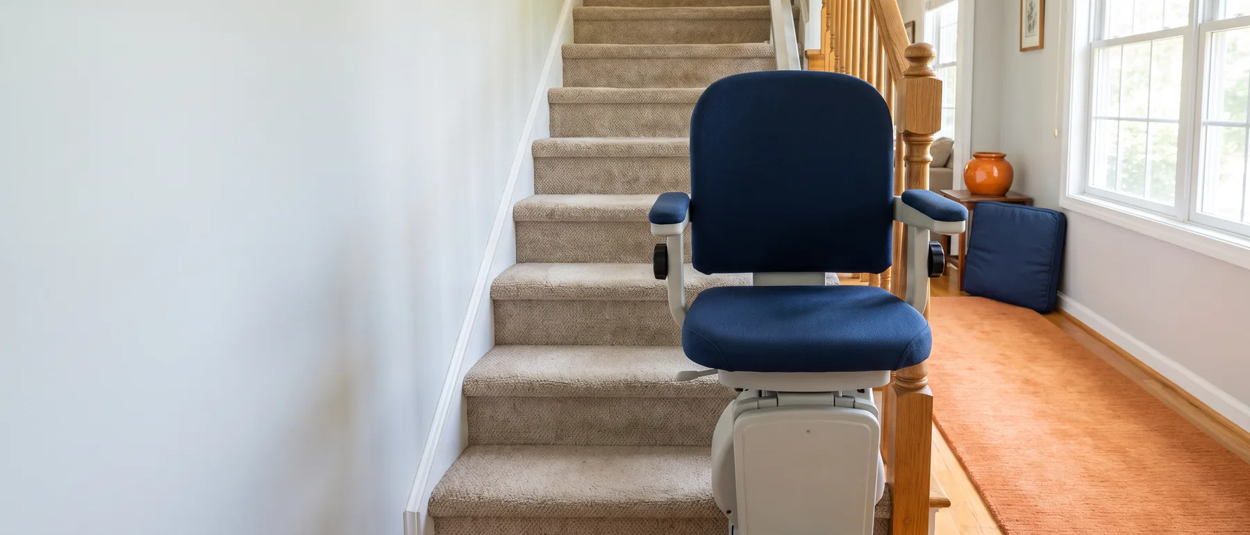 A sturdy stair lift with a wide padded seat on a straight staircase