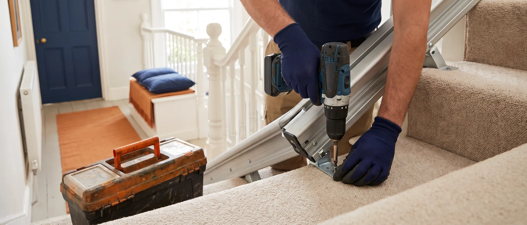 An installer fastening a stair lift rail bracket to a stair tread