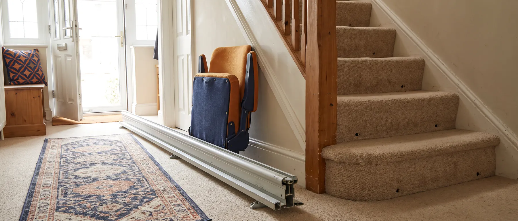 A stair lift rail taken off the stairs and laid in the hallway, with screw holes left in the carpet