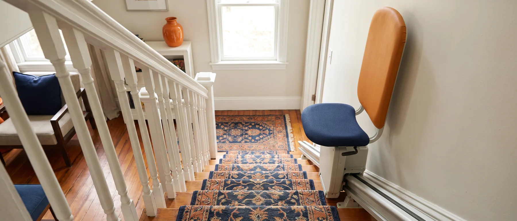 A perch stair lift with a small saddle seat on a steep narrow staircase