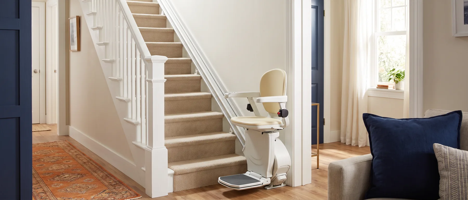 A stair lift parked at the foot of a straight carpeted staircase