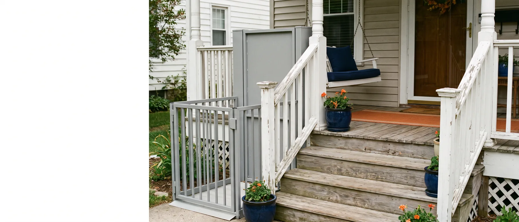 A vertical platform wheelchair lift beside the porch steps of a house